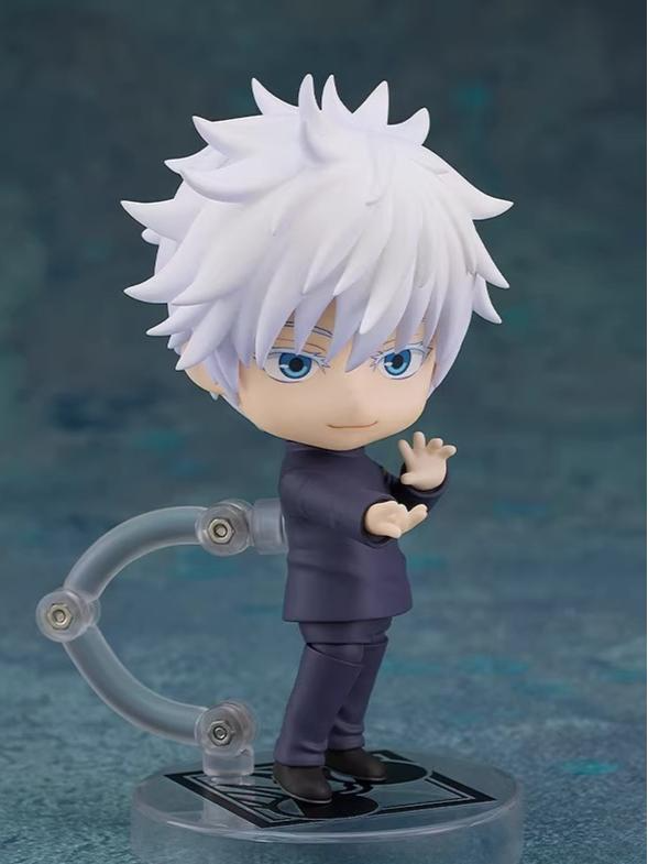 The Jujutsu Kaisen Gojo Satoru Action Figure is a 12cm chibi-style anime collectible with spiky white hair and blue eyes. Dressed in a dark outfit, it has one arm extended and stands on a clear plastic base against a blue textured background, perfect for fans.