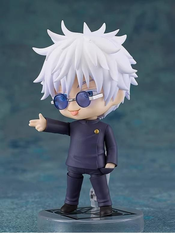 The Gojo Satoru Action Figure, a 12cm chibi-style collectible from Jujutsu Kaisen, features spiky white hair and glasses with a dark outfit. Standing on a circular base against a blurred blue background, its movable joints make it an essential anime collectible.