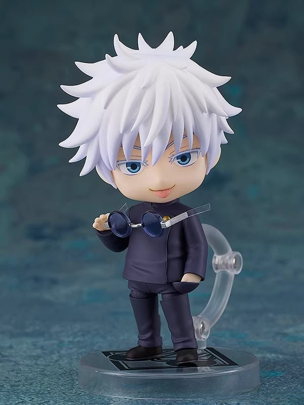The Gojo Satoru Action Figure is a 12cm Jujutsu Kaisen collectible with spiky white hair, blue eyes, and a smirk. It wears a dark outfit, holds round glasses, and is mounted on a clear stand with a blue background—ideal for Jujutsu Kaisen fans.