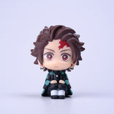 This 7cm chibi-style figure from the Demon Slayer Figure Set - 8-Piece PVC Anime Collection showcases a character with spiky dark hair, a red forehead mark, large red eyes, and a green and black outfit, seated with hands in lap against a white backdrop.