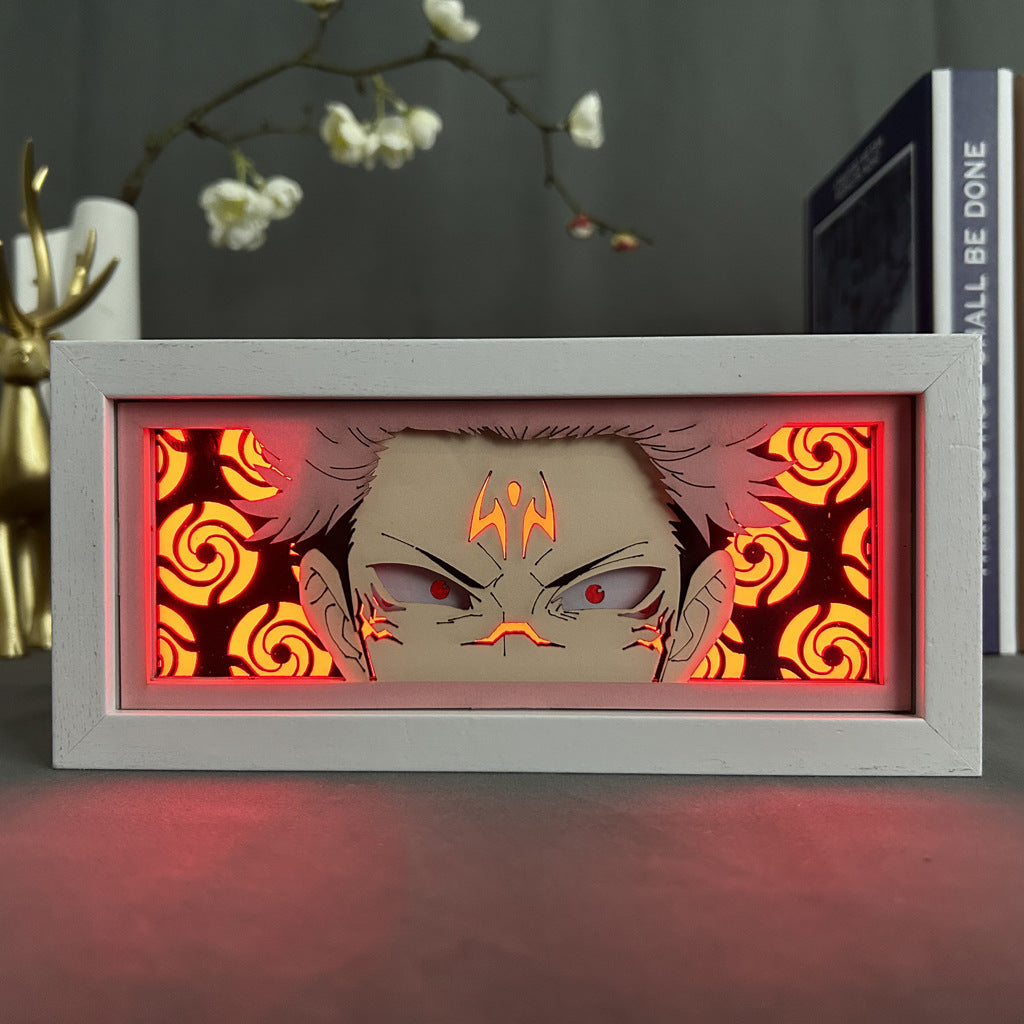 The Jujutsu Kaisen Anime Light Box features Sukuna with tribal markings and piercing eyes, set against an orange swirling pattern. Decorative antlers and a flowering branch complete the scene. It offers a 3D effect with adjustable 16-color LED lighting for dynamic display.