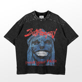 The Solo Leveling Betrayed Prove Your Faith T-Shirt features a graphic of a blue-skinned, wide-grinning face, with red text above and below. It has a vintage mineral wash texture that&