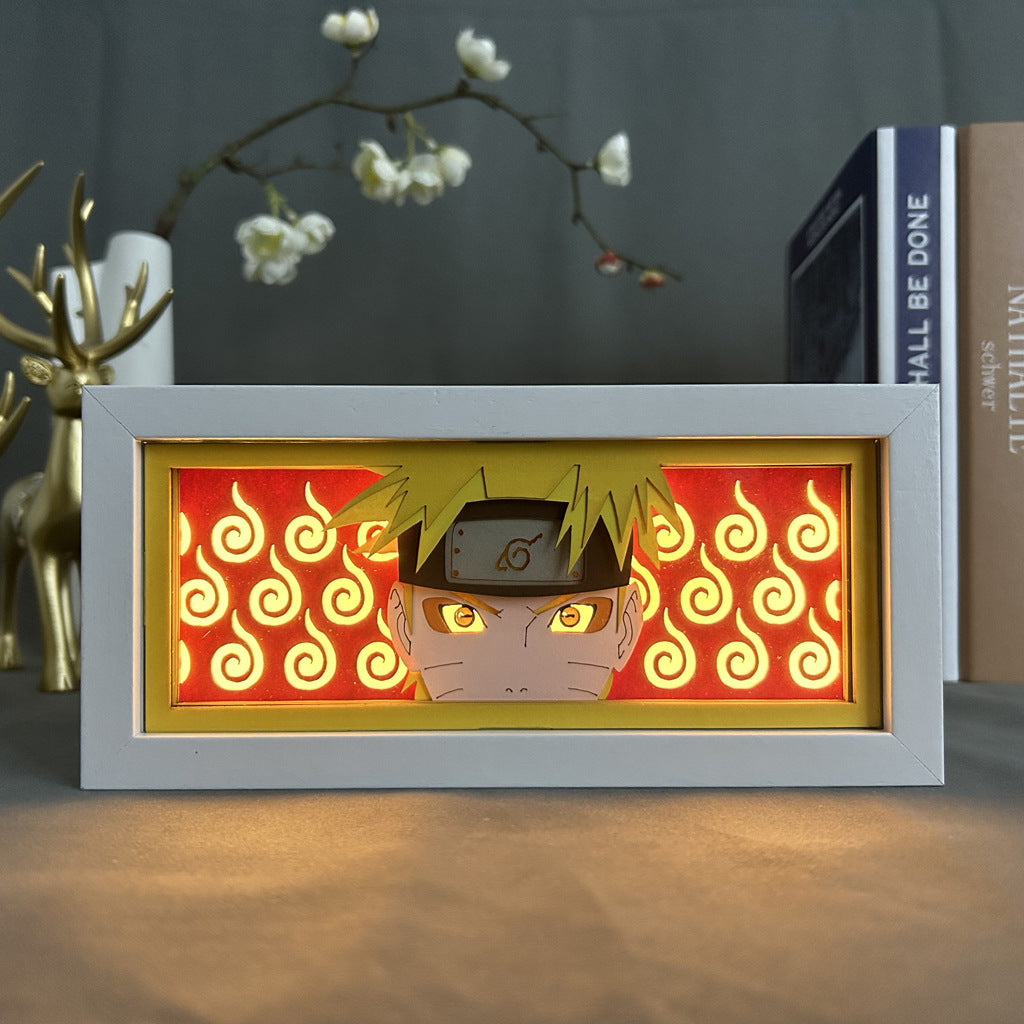 The Naruto Anime Light Box by My Hero Academia features a framed illustration of Uzumaki Naruto with a headband, set against an orange swirl background. Enhanced by a 16-color adjustable LED, the artwork achieves a 3D effect. A decorative deer figurine and vase complete the ambiance.