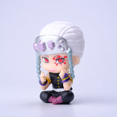 The Demon Slayer Figure Set features a striking 7cm figure from the Kimetsu no Yaiba collection. It includes an anime character with fiery red eyes, silver headpiece, black outfit, and uniquely styled white hair in a seated pose, ideal for any discerning collection.