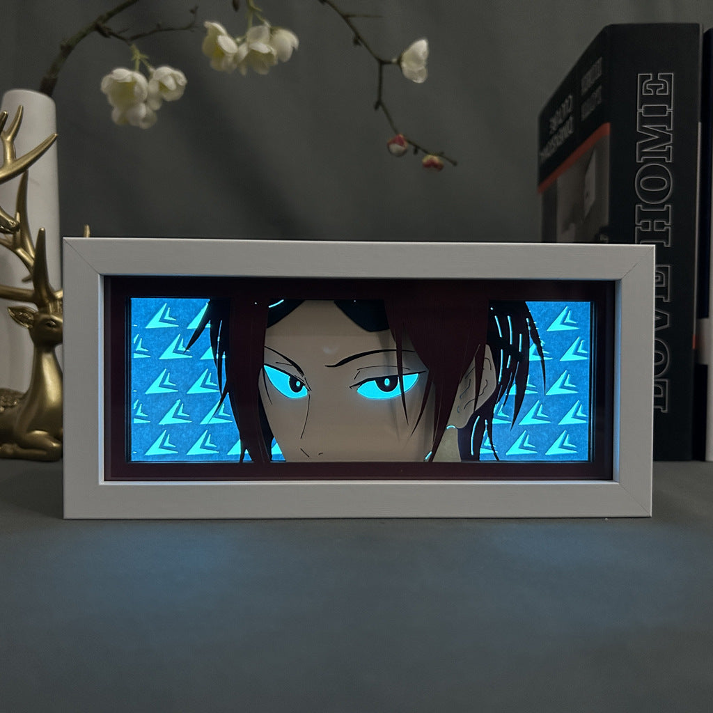 The Blue Lock Anime Light Box features a 3D LED lamp of Rin Itoshi with red hair and glowing blue eyes against a geometric background. It sits on a table beside a decorative deer and the book "Love Home," showcasing dynamic color-changing effects.