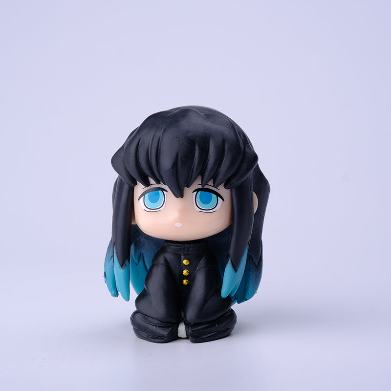 The Demon Slayer Figure Set features chibi-style characters, including one with long black hair, blue eyes, and blue highlights. Displayed against a white background and dressed in a black outfit with yellow buttons, this simplistic design is perfect for any anime collection.