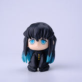 The Demon Slayer Figure Set features chibi-style characters, including one with long black hair, blue eyes, and blue highlights. Displayed against a white background and dressed in a black outfit with yellow buttons, this simplistic design is perfect for any anime collection.