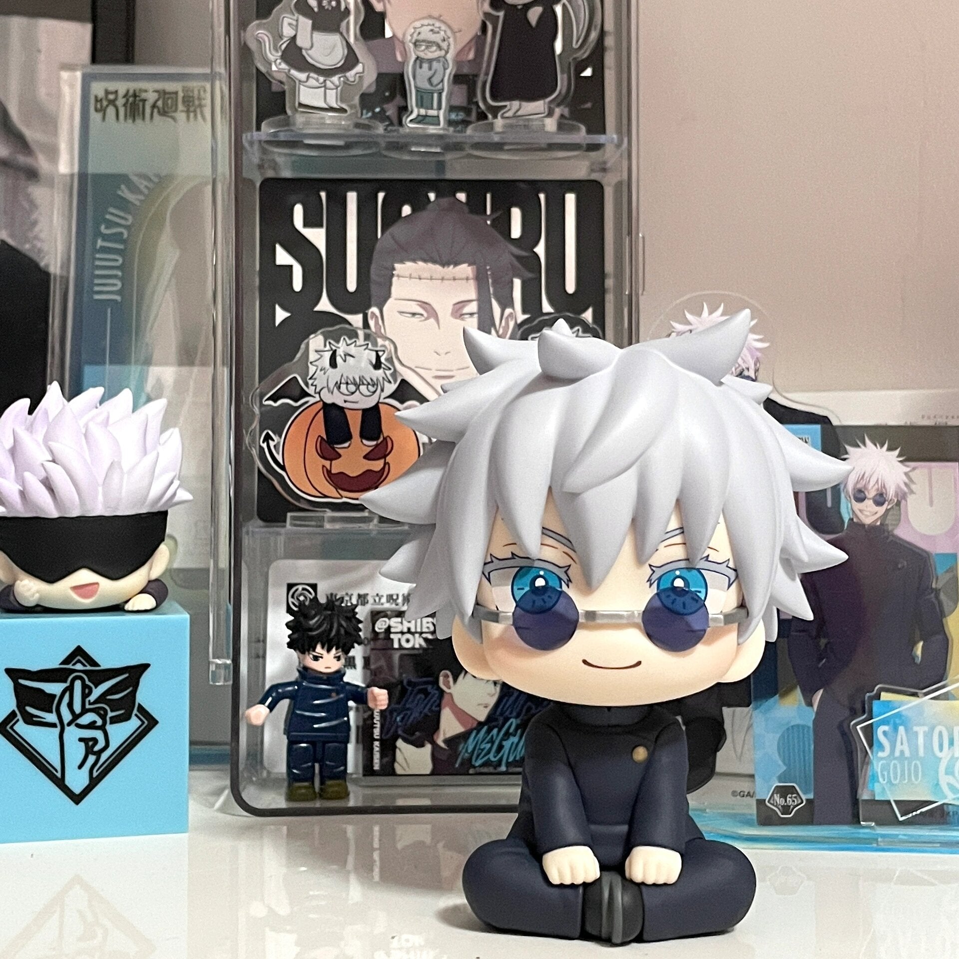 The Jujutsu Kaisen Gojo Satoru Anime Figure features a 12cm chibi with white hair and blue eyes, perfect for anime collections. This collectible action figure is surrounded by smaller characters with white spiky hair and black outfits.