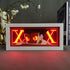 The Hunter × Hunter Anime Light Box showcases Gon Freecss with red eyes and a neon X theme, set against a dark backdrop. Nearby, find a small plant and an ornate deer statue beside a book titled "THAT JUSTICE SHALL BE DONE." This 16-color LED piece embodies the intensity of *Hunter x Hunter*.