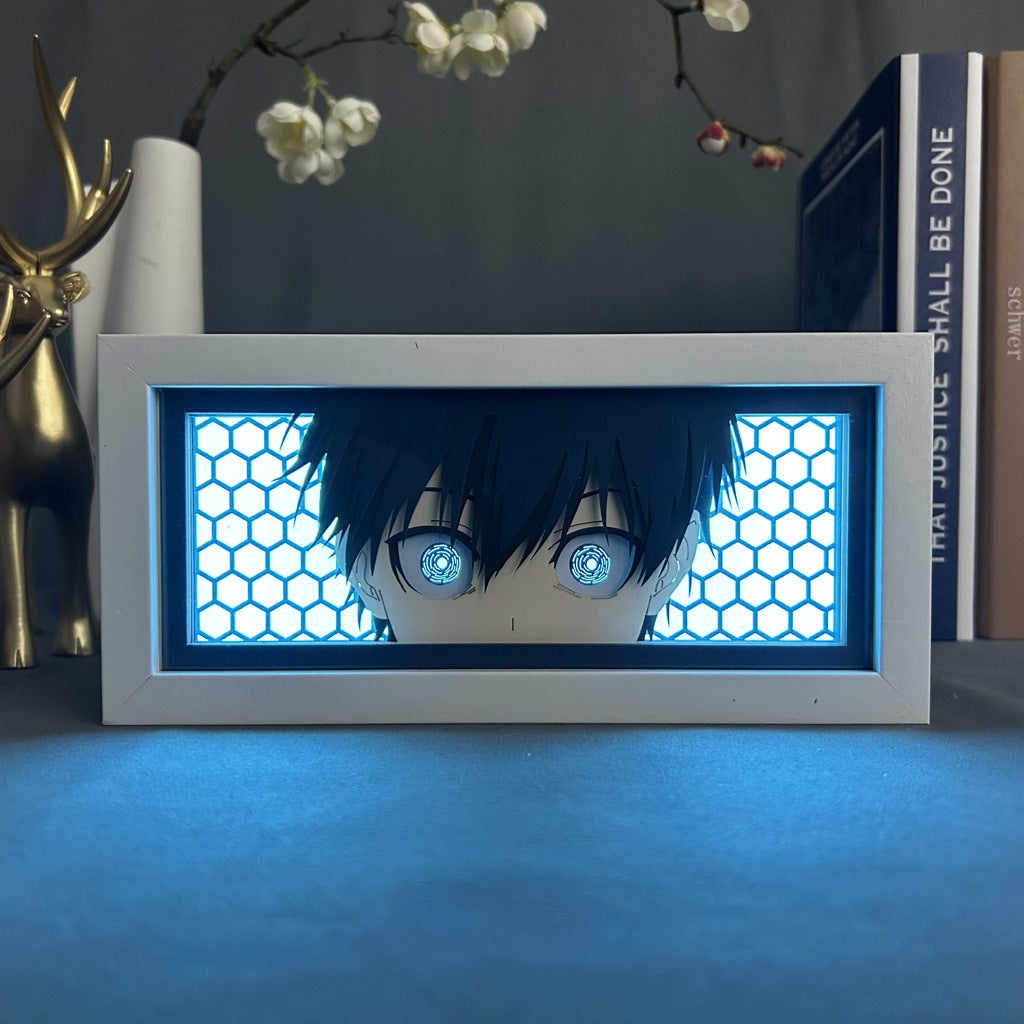 The Seakoff Hypnotic Blue-Eyed Anime Light Box features a hexagonal pattern and 16-color customizable LED glow, adding a futuristic touch. It sits on a table with books and a golden deer figurine, framed by flowers in the background.