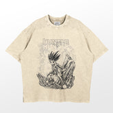 The Hunter x Hunter Gon Freecss Washed Vintage T-Shirt features a beige design with a black and white illustration of a spiky-haired character, surrounded by stylized rocks and crystals. The word "Hunter" elegantly adorns the shirt, capturing the vintage anime vibe in this high-quality cotton streetwear.