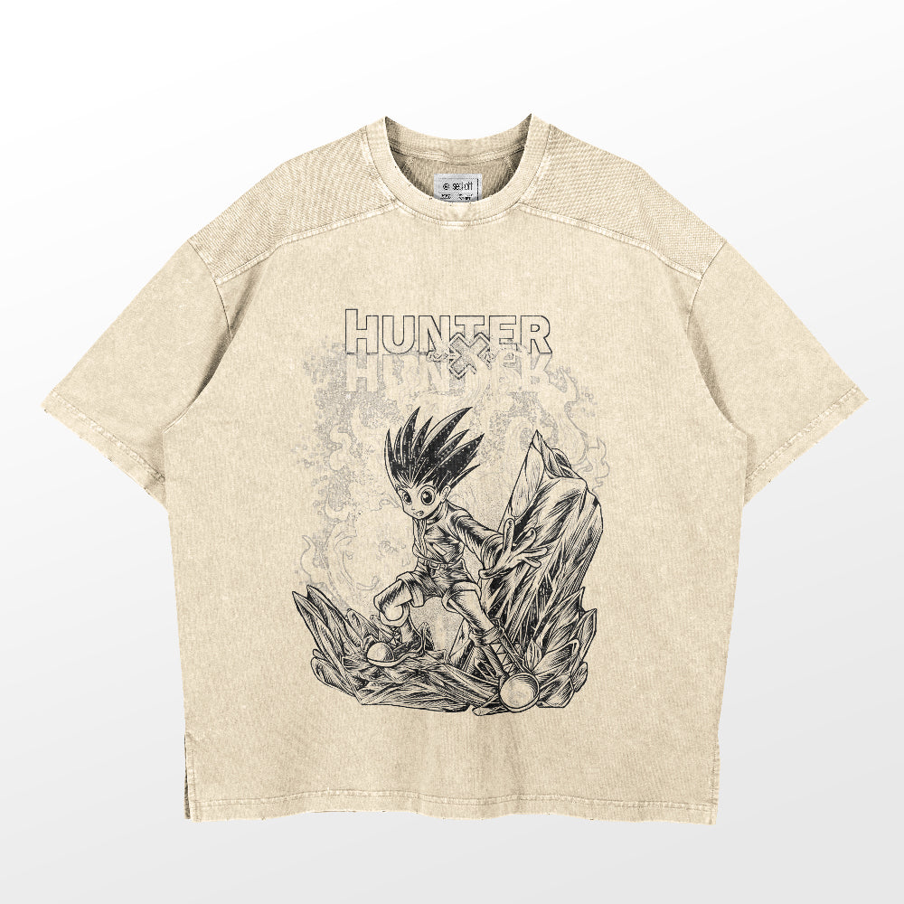The Hunter x Hunter Gon Freecss Washed Vintage T-Shirt features a beige design with a black and white illustration of a spiky-haired character, surrounded by stylized rocks and crystals. The word "Hunter" elegantly adorns the shirt, capturing the vintage anime vibe in this high-quality cotton streetwear.