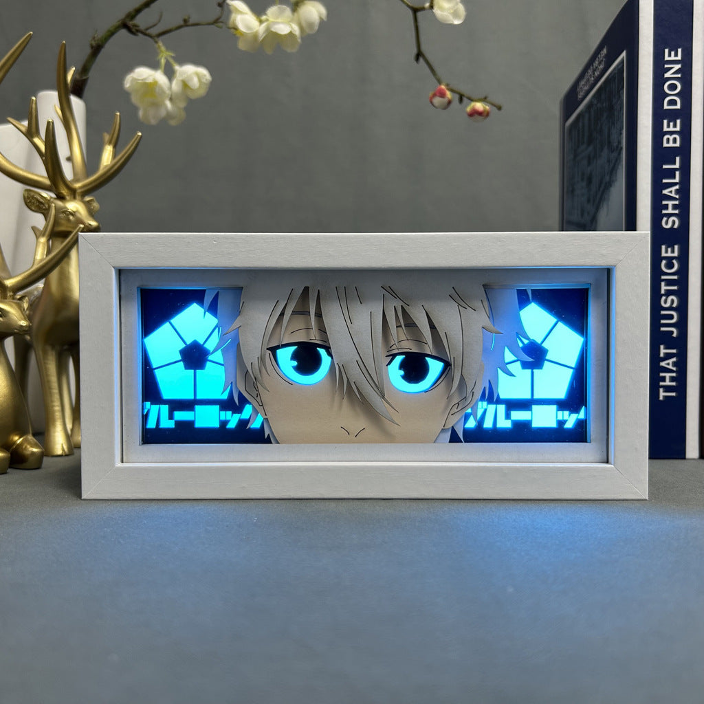 The Isagi Yoichi Anime Light Box from Blue Lock features a character with white hair and large blue eyes against a blue geometric background, sitting beside a golden reindeer figurine and the book "THAT JUSTICE SHALL BE DONE," adding anime decor charm.