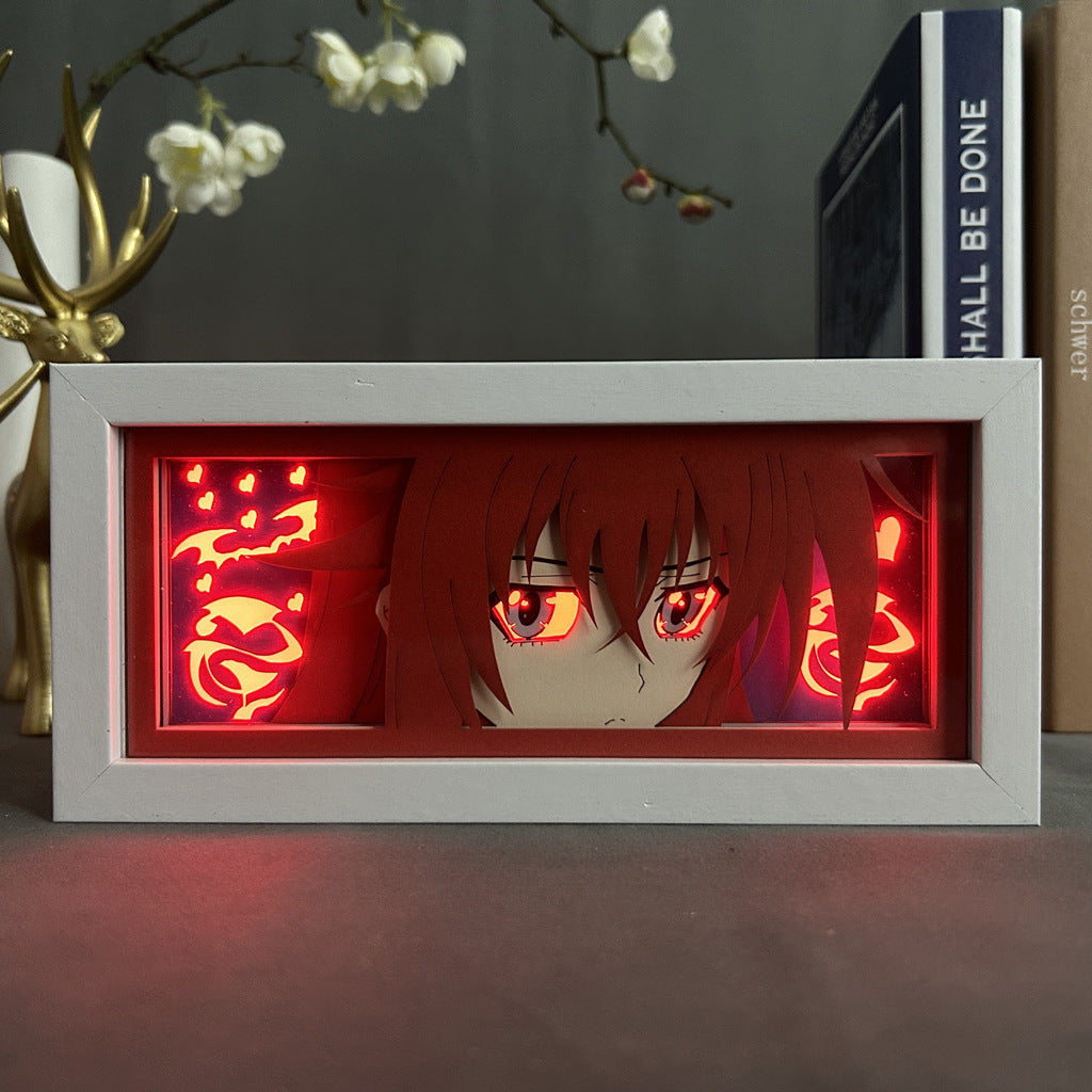 The Rias Gremory LED Light Box by High School DxD showcases her red hair and eyes against a fiery background. Displayed on a table with flowers, the book "Shall Be Done," and a gold antler ornament, it perfectly captures the essence of High School DxD in 3D LED brilliance.