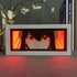 A framed piece on a shelf features a character with intense eyes and dark hair against a red-orange background, ideal for Spy × Family fans. With floral branches and a decorative deer antler stand, it pairs perfectly with your Yor Forger LED Light Box – Spy x Family 3D Anime Lamp.