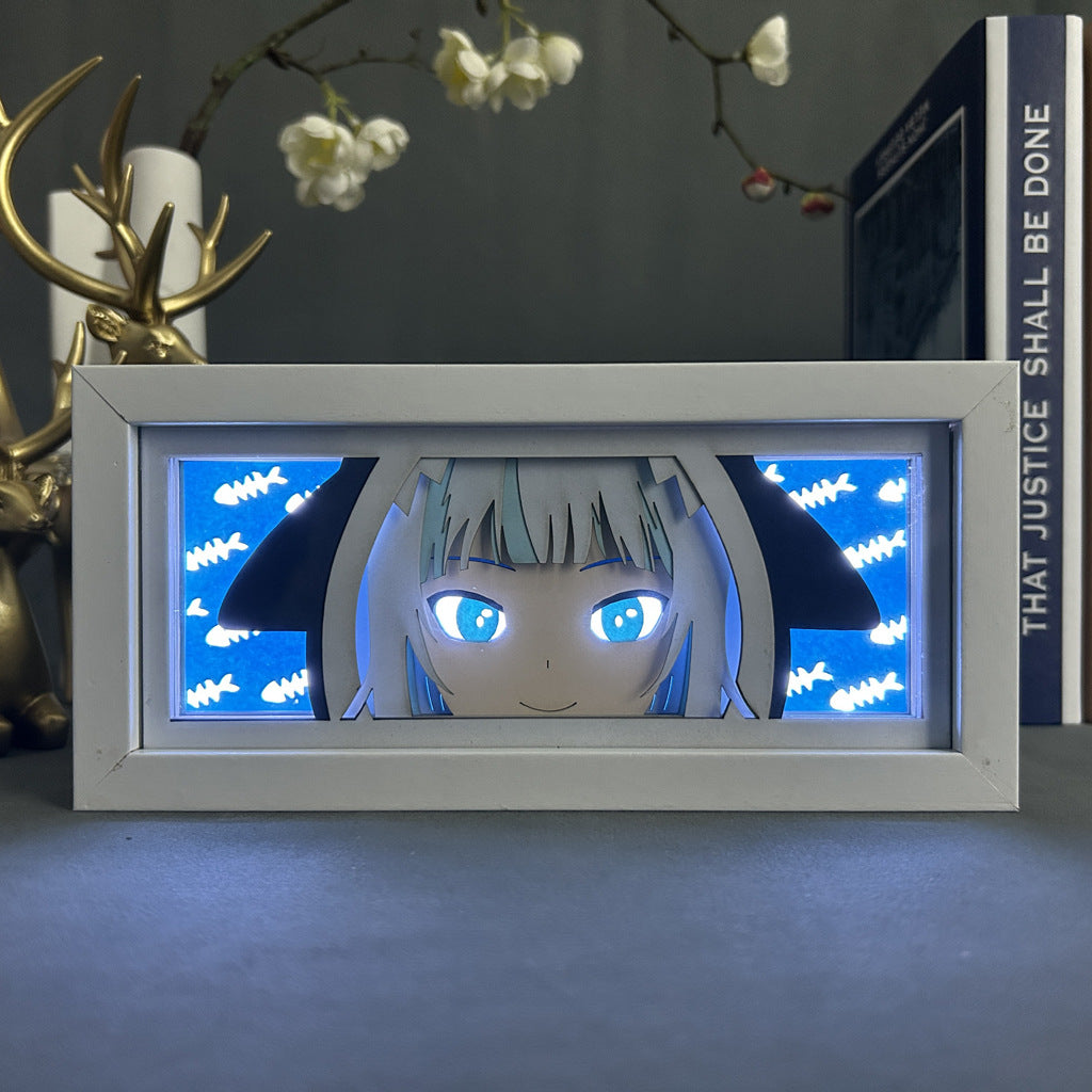The Seakoff Shark-Themed Anime LED Light Box features a 3D lamp with an anime character having blue eyes, white hair, and black ears. A small fish pattern on a blue background and a decorative gold deer create an enchanting atmosphere with books enhancing the decor.