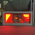 The Chainsaw Man Anime Light Box – Power 3D LED Lamp features a character with long hair and a surprised expression, enhanced by red hues and dynamic color-changing effects. Books and decor in the background add charm, reminiscent of an anime light box.