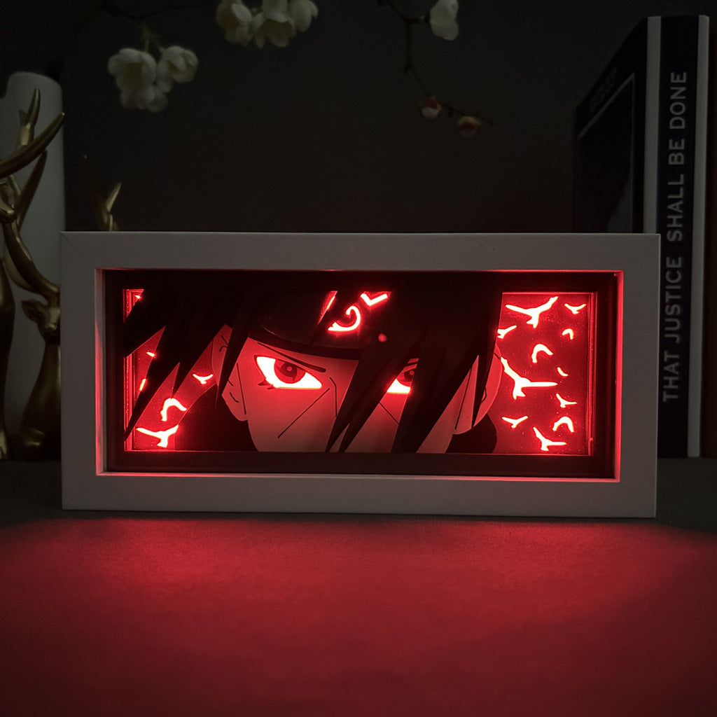 The Naruto Anime Light Box – Itachi Uchiha 3D LED Lamp by Naruto displays Itachi with intense eyes among red shapes. Silhouetted branches with white flowers are in the background, alongside a book labeled "THAT JUSTICE SHALL BE DONE," enhanced by dynamic color-changing effects.