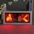 A rectangular frame showcases a Chainsaw Man Anime Light Box, featuring Denji in his chainsaw form. Its split-face design contrasts human and robotic elements with dynamic color-changing effects, enhanced by a fiery red background. Nearby are books, a white vase, and a golden deer figurine.