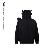 The Seakoff Cute Night Fury Dragon Hoodie, styled after the beloved dragon with 3D ears and a small black plush on the shoulder, features "LOOKING FOR HUMANS" text and a silhouette. Perfect for anime fans!.