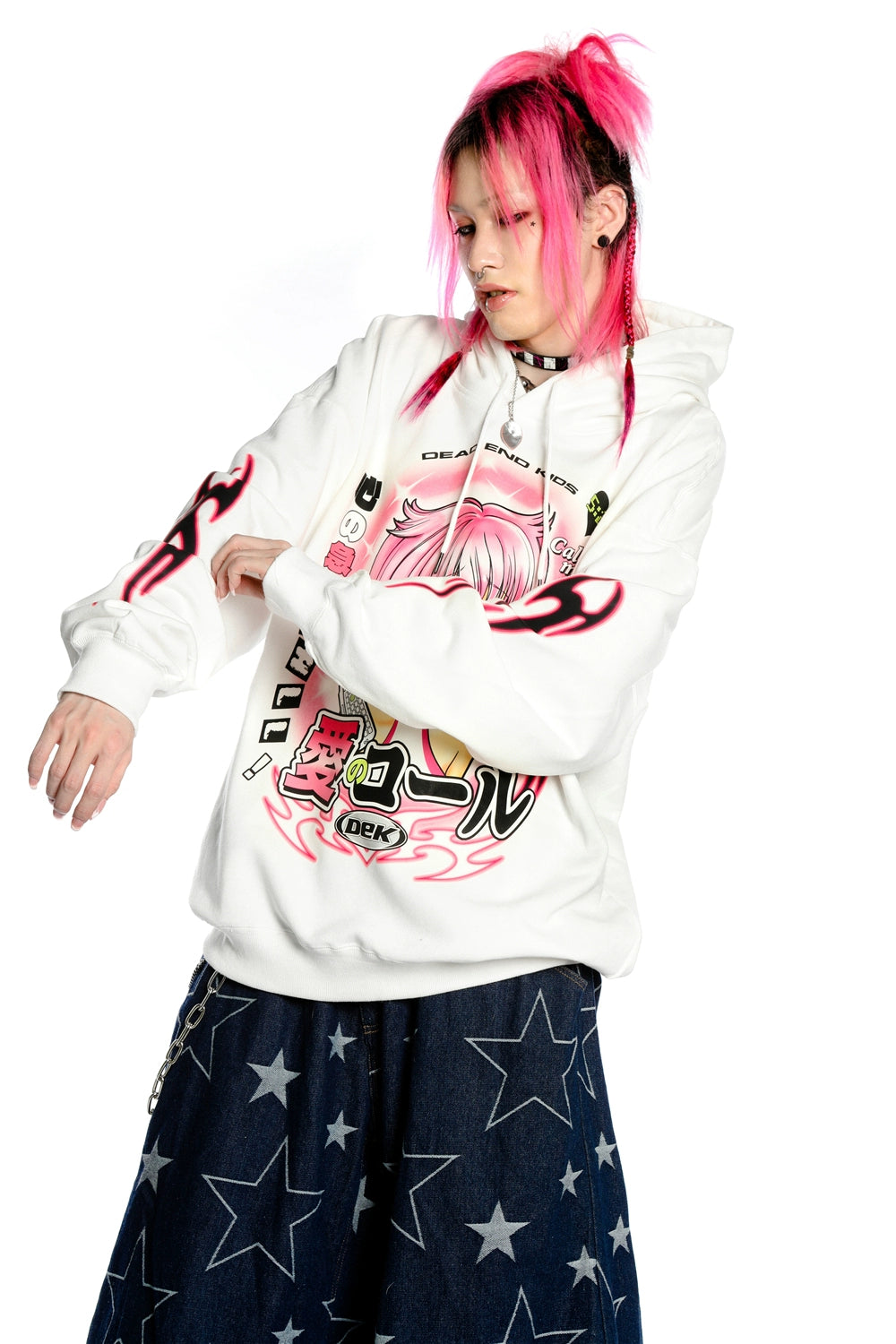 A person with pink hair in braided pigtails is wearing the Seakoff Y2K Aesthetic Anime Hoodie, a retro manga girl graphic pullover with kawaii phone design. Their dark star-patterned pants enhance their Y2K style against a crisp white background.