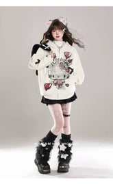 A person in a white Seakoff Gothic Hello Kitty Princess Hoodie, featuring edgy heart and cross graphics, poses against a plain background embodying kawaii fashion. They wear a black skirt, furry black leg warmers, a cat ear headband, and have long hair. Their arms are slightly spread with legs crossed at the ankles.