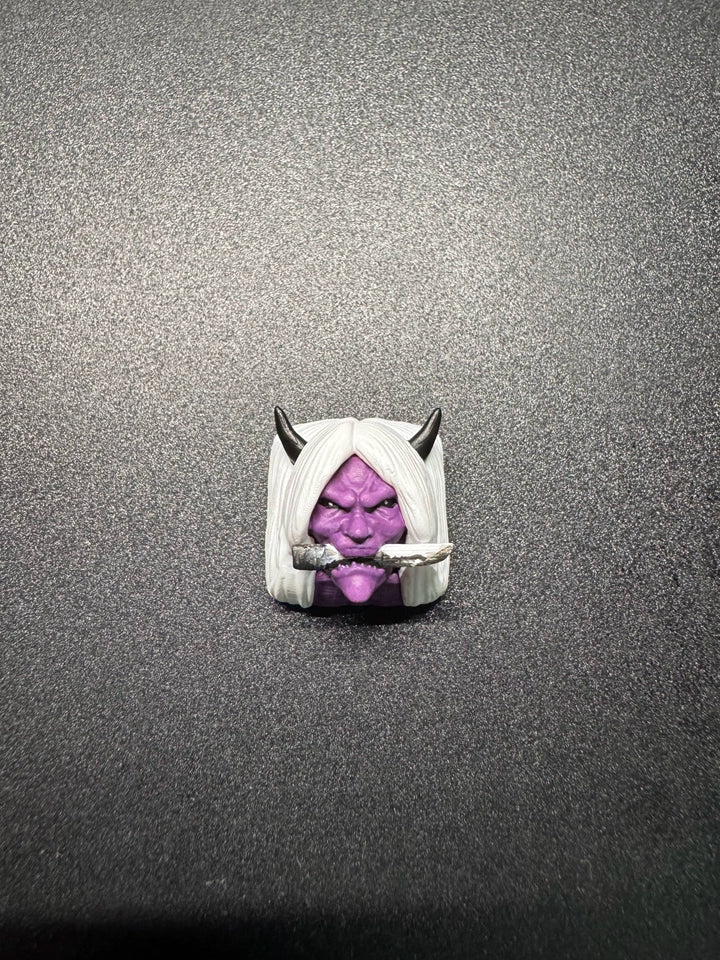 A small figurine of a purple-faced character with white hair, black horns, and a cigar in its mouth, placed on a dark textured surface.
