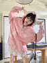 A person playfully poses indoors wearing the Seakoff Kawaii Star Elf Hoodie, featuring cute 3D ear details and soft star appliques. In the minimalistic, neutral-toned room, they stand near a table and shelf holding a metallic bag.