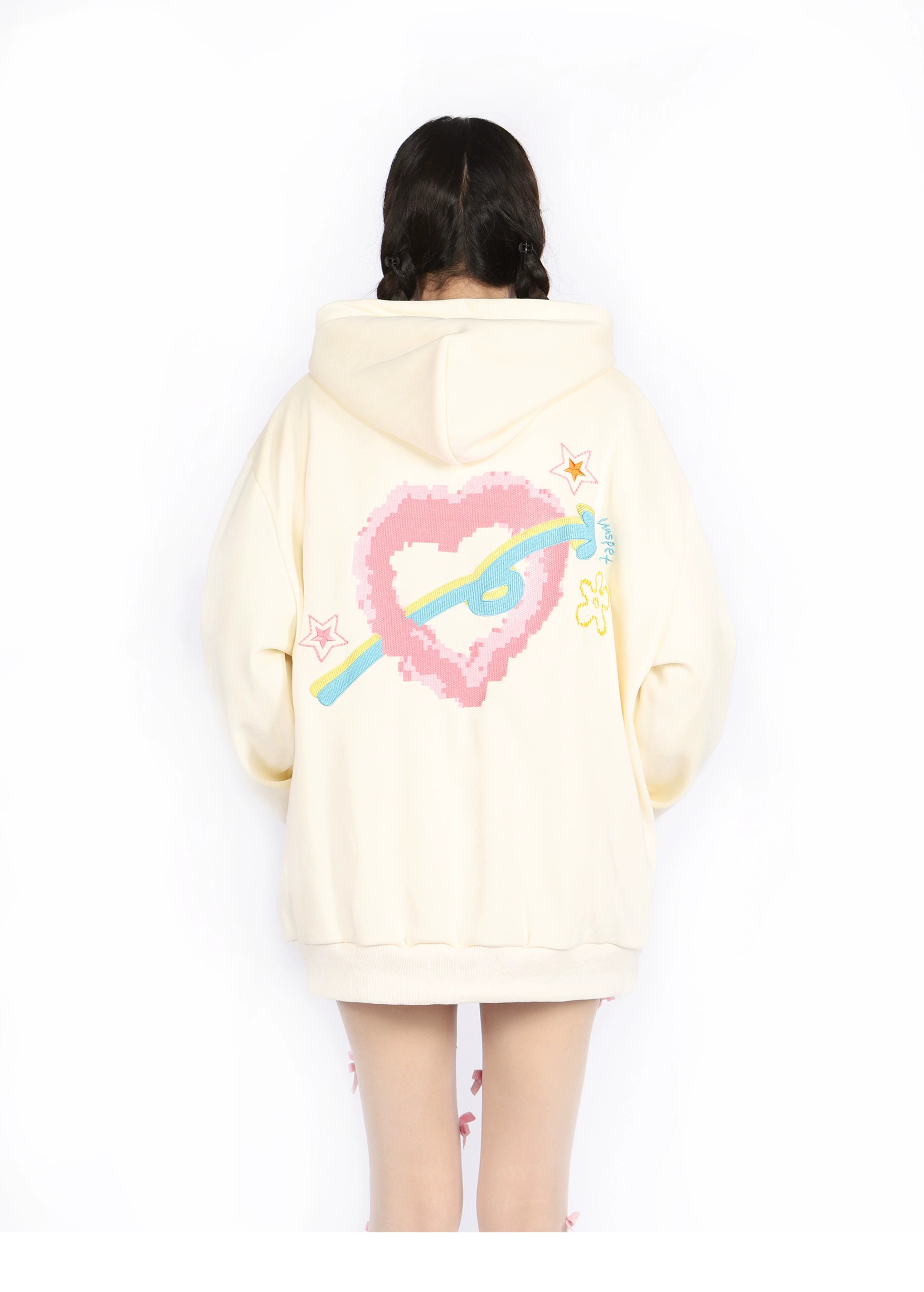 Someone wearing the Seakoff Kawaii Pastel Cartoon Hoodie with a pixelated heart and planet design stands back to the camera. This cream hoodie features pink and blue accents, small stars, and embodies anime fashion for a charming look.
