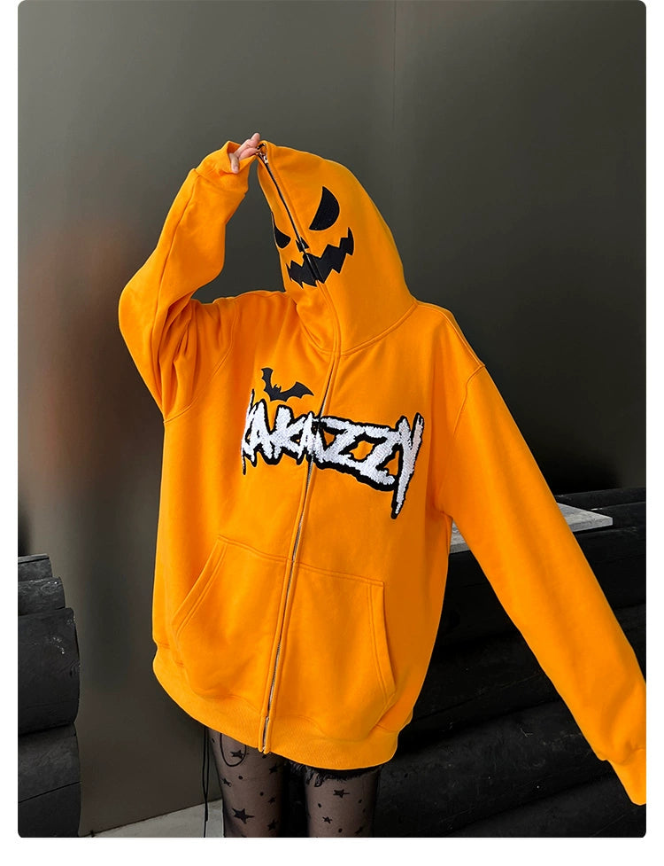 A person is wearing an oversized orange pumpkin hoodie from Seakoff, featuring a jack-o&