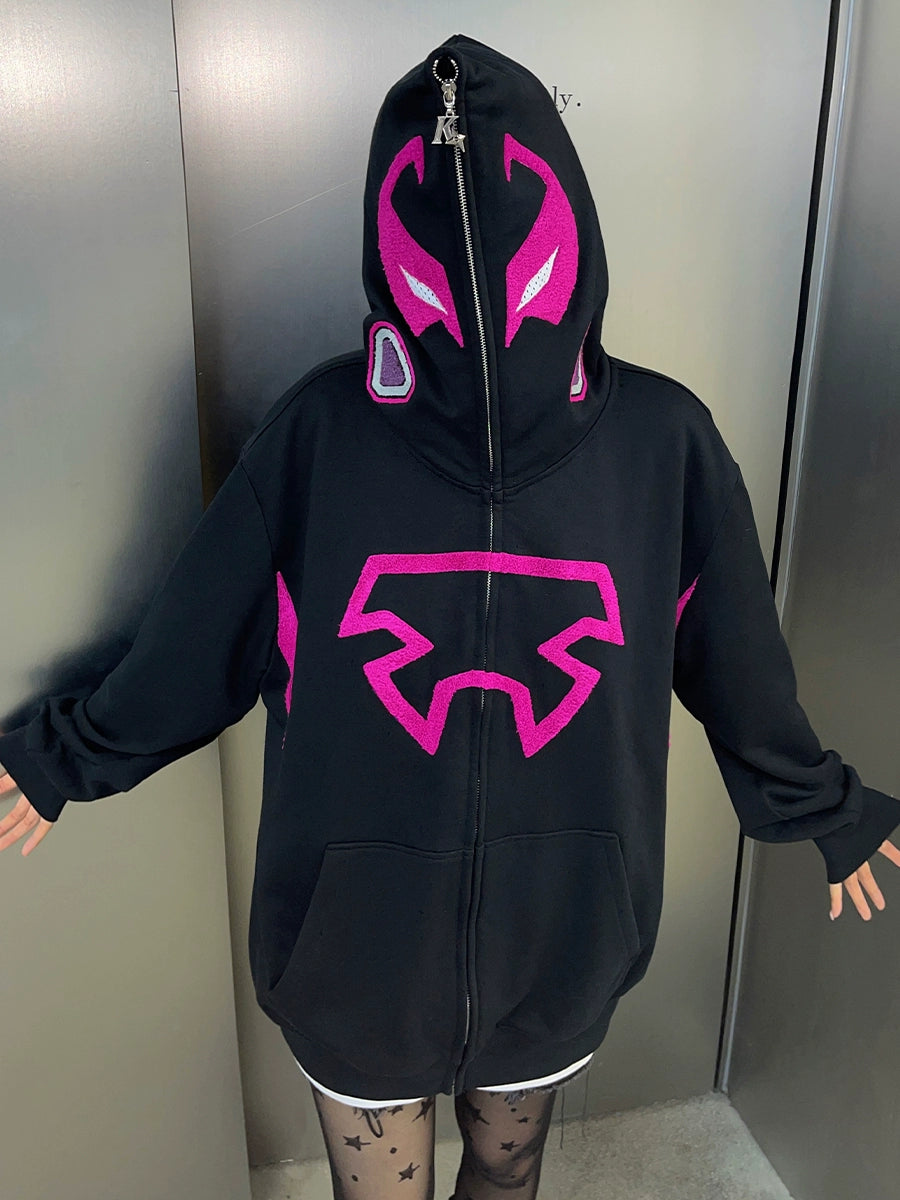 A mysterious figure in a Seakoff Futuristic Warrior Hoodie stands against a plain backdrop. The 400GSM oversized sci-fi pink and black zip-up sweatshirt features purple accents and abstract designs, creating an avant-garde look when paired with patterned tights.