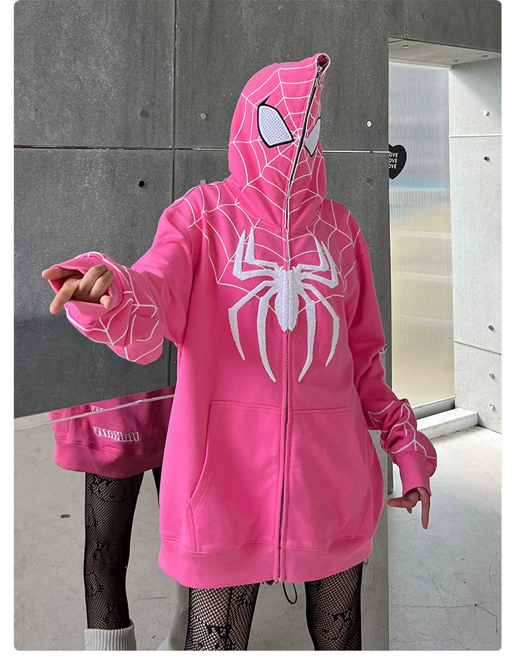 A person in a Seakoff Spider-Inspired Hoodie, crafted from 400GSM cotton with a white spider design and web-patterned hood, poses with an extended hand. The outfit features fishnet leggings and white socks against a gray metallic wall backdrop that superhero fans will adore.