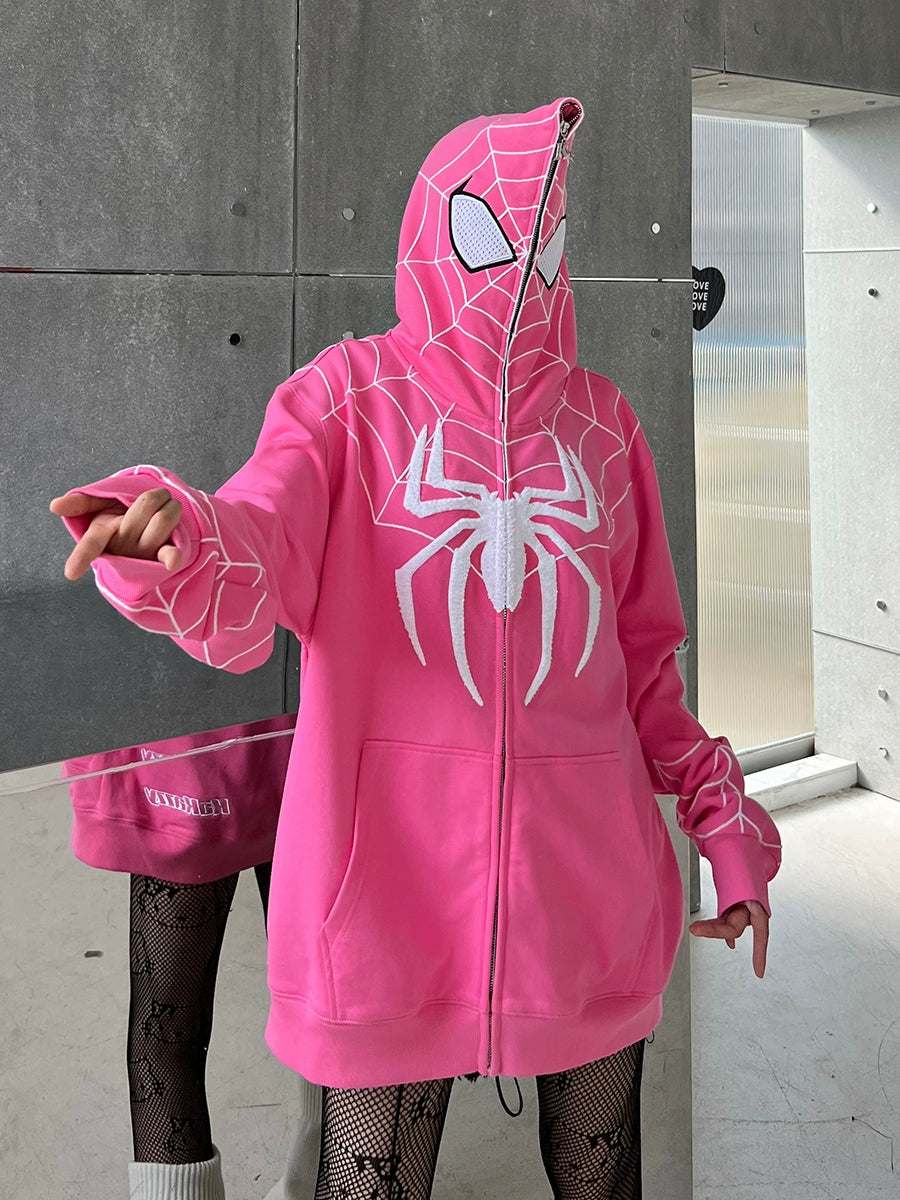 A person confidently wearing a Seakoff Spider-Inspired Hoodie—a 400GSM oversized pink zip-up superhero sweatshirt—stands pointing forward with their right hand. Paired with fishnet stockings, they pose against an industrial wall, perfectly embodying a heroic vibe for fans.