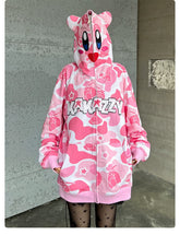 A person wears a Seakoff Pink Kirby-Inspired Hoodie featuring a trendy camo print, 3D ears, and "KAKAZZY" text, paired with star-patterned black tights for a playful look.