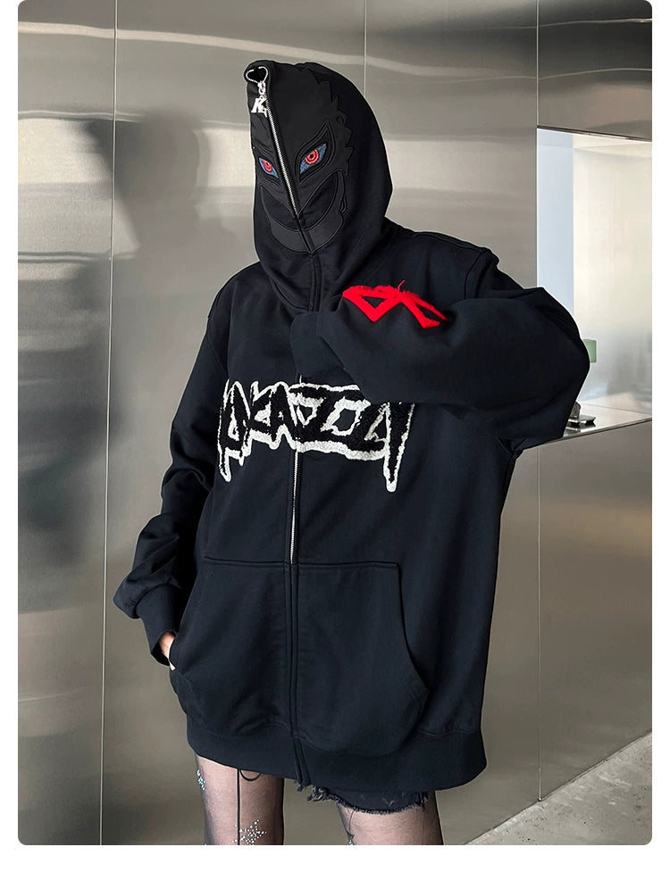 A person sports a Berserk-Inspired Griffith Dark Knight Hoodie—400GSM, black, zip-up, oversized streetwear with a front graphic. The hood includes a mask with red eyes. They stand against a metallic wall, wearing fishnet stockings under shorts.