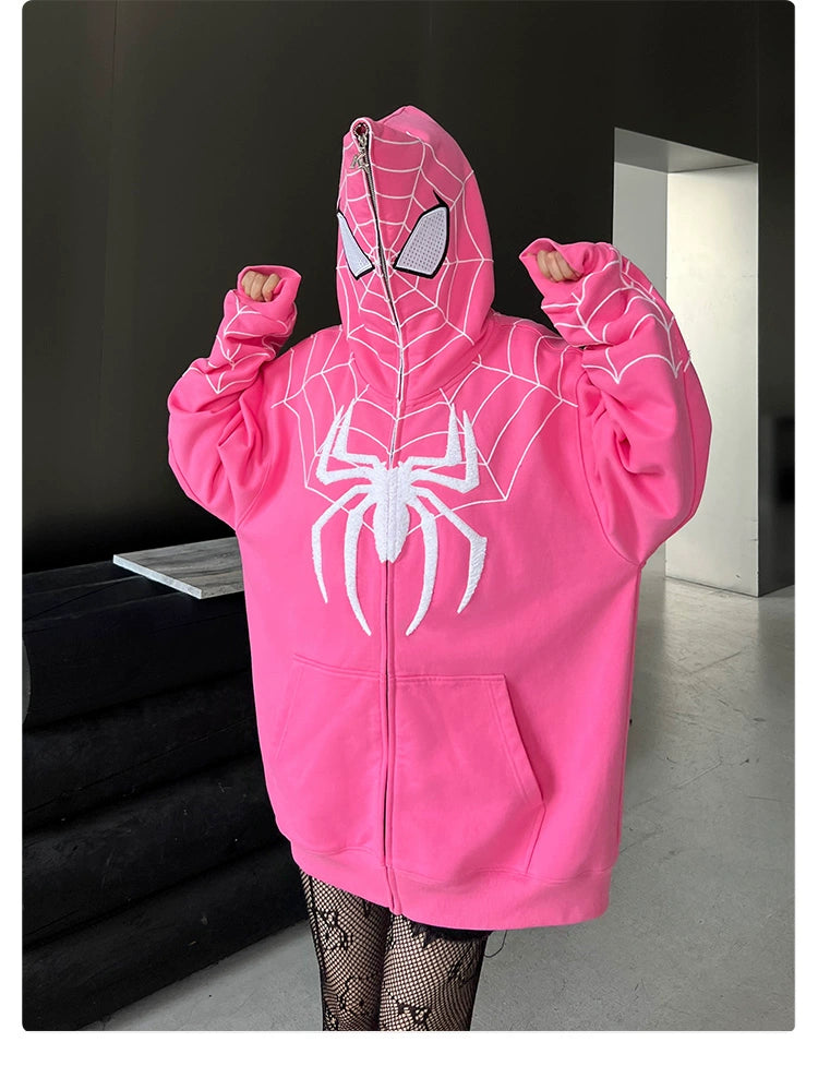 Wearing the Seakoff Spider-Inspired Hoodie made from 400GSM cotton, a person showcases its bold pink hue, spider web pattern, and iconic white spider logo. With the hood fully zipped and sleeves held playfully high, it&