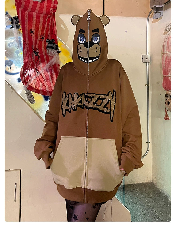 A person wears a Freddy-inspired hoodie from Seakoff, an oversized 400GSM brown zip-up sweatshirt for Five Nights at Freddy&