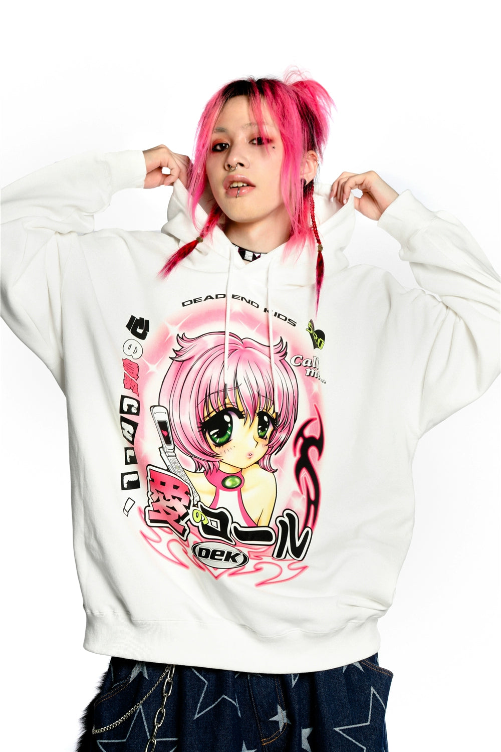 A person with pink hair wears a Seakoff Y2K Aesthetic Anime Hoodie, featuring a retro manga girl with pink hair, large green eyes, and a kawaii phone design. The hoodie blends text and graphics in perfect kawaii style as they stand against a plain white background.