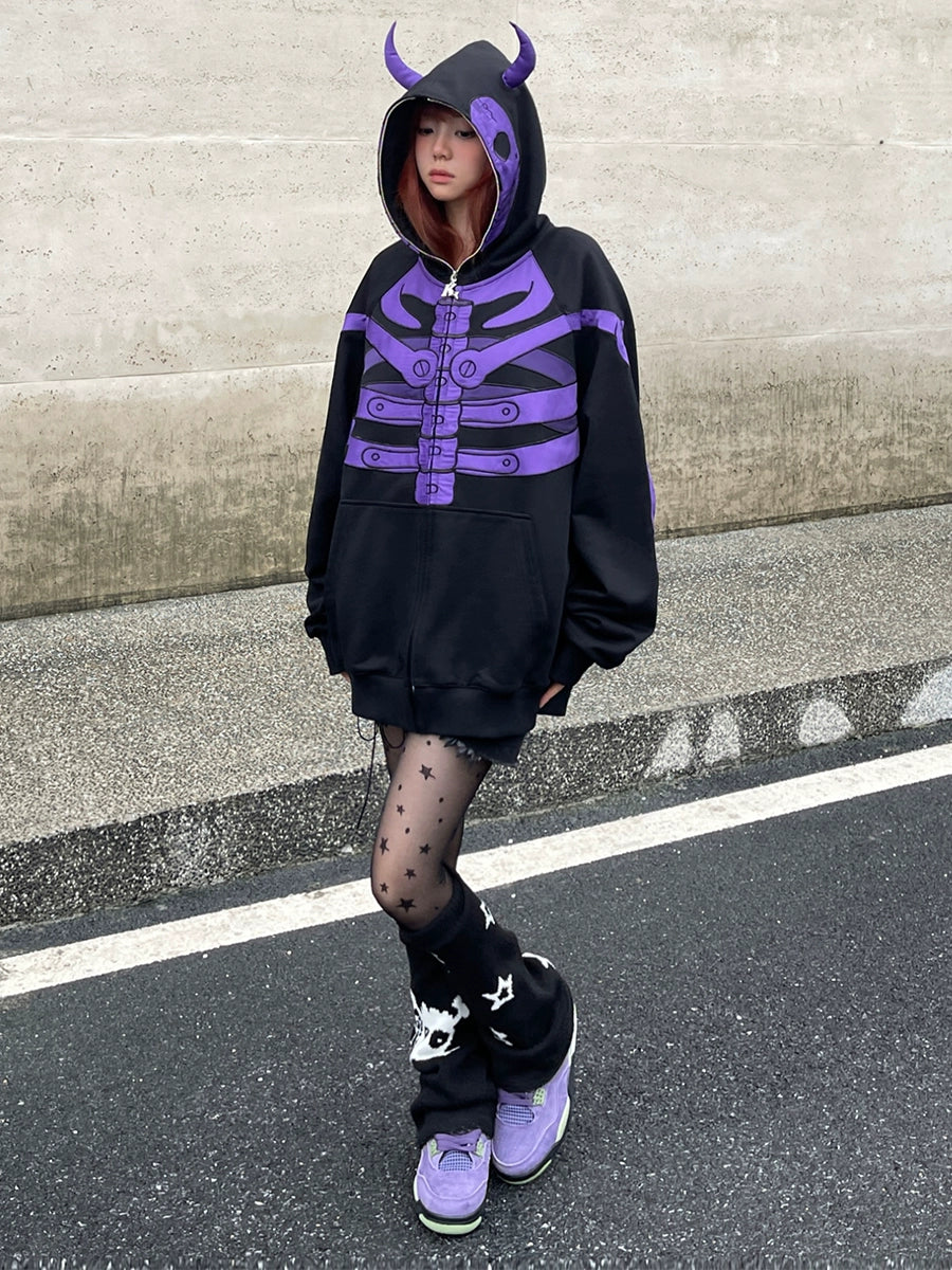 A person stands on a street wearing the Seakoff Dark Skull Demon Hoodie, a 400GSM oversized zip-up anime-inspired sweatshirt with a purple skeleton design and horned hood, paired with star-patterned tights and purple sneakers, against a concrete wall backdrop.