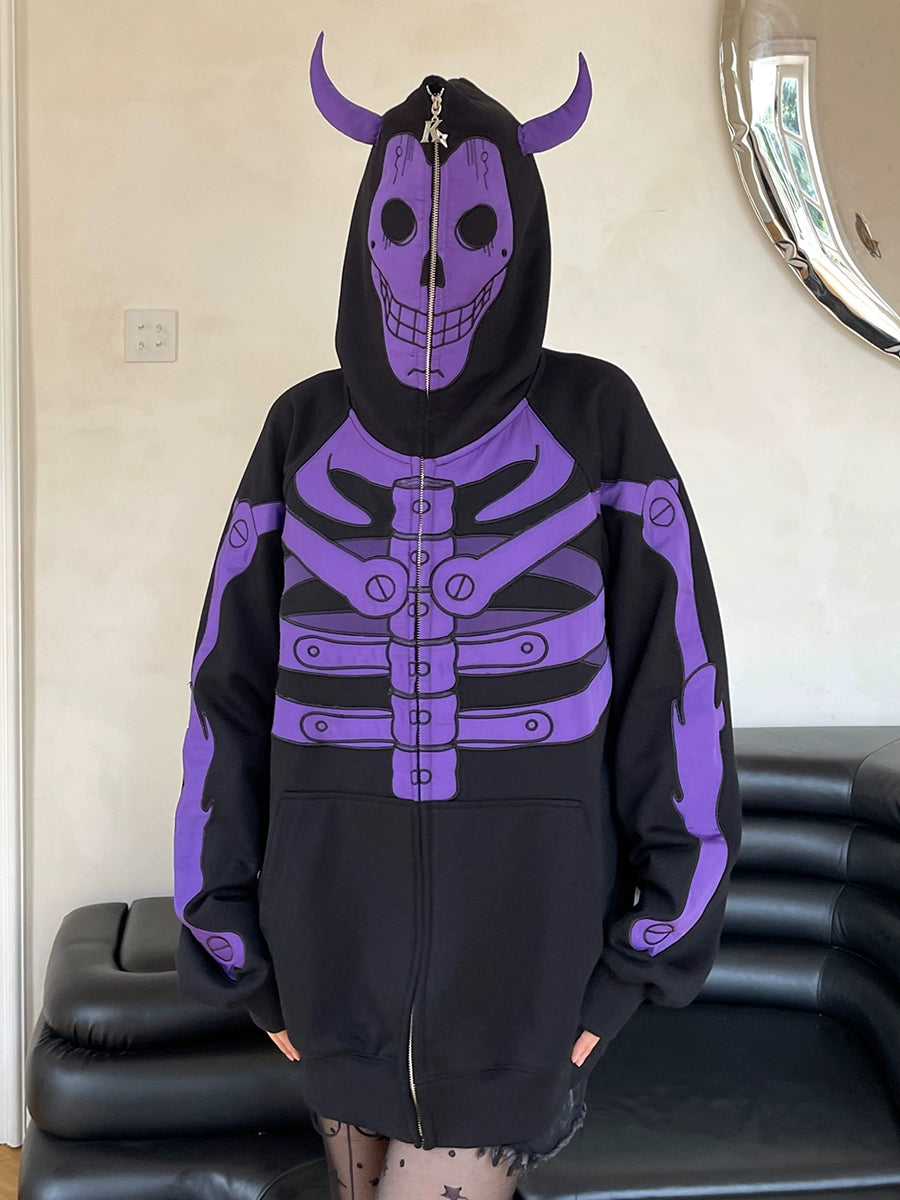 Wearing a Seakoff Dark Skull Demon Hoodie, a black and purple 400GSM oversized anime-inspired zip-up with skeleton design, skull hood, and ribcage detailing, a person stands against a light wall near a black couch and decorative mirror in Gothic fashion.