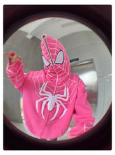 A fun fisheye photo shows a person in a 400GSM Seakoff Spider-Inspired Hoodie, an oversized bright pink superhero sweatshirt. It features a white web pattern and a zip-up hood that cleverly covers the face with mesh over the eyes.