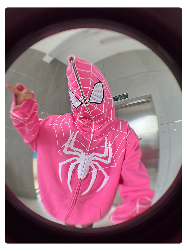 A fun fisheye photo shows a person in a 400GSM Seakoff Spider-Inspired Hoodie, an oversized bright pink superhero sweatshirt. It features a white web pattern and a zip-up hood that cleverly covers the face with mesh over the eyes.