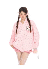 A person poses winking, embracing kawaii fashion in a Seakoff Hello Kitty Pink Kawaii Hoodie—a cute oversized zip-up with cat ear hood and all-over print. Paired with pink shorts, skirt, lace-patterned tights, and braided hair, they hold a sheer bag filled with colorful items.