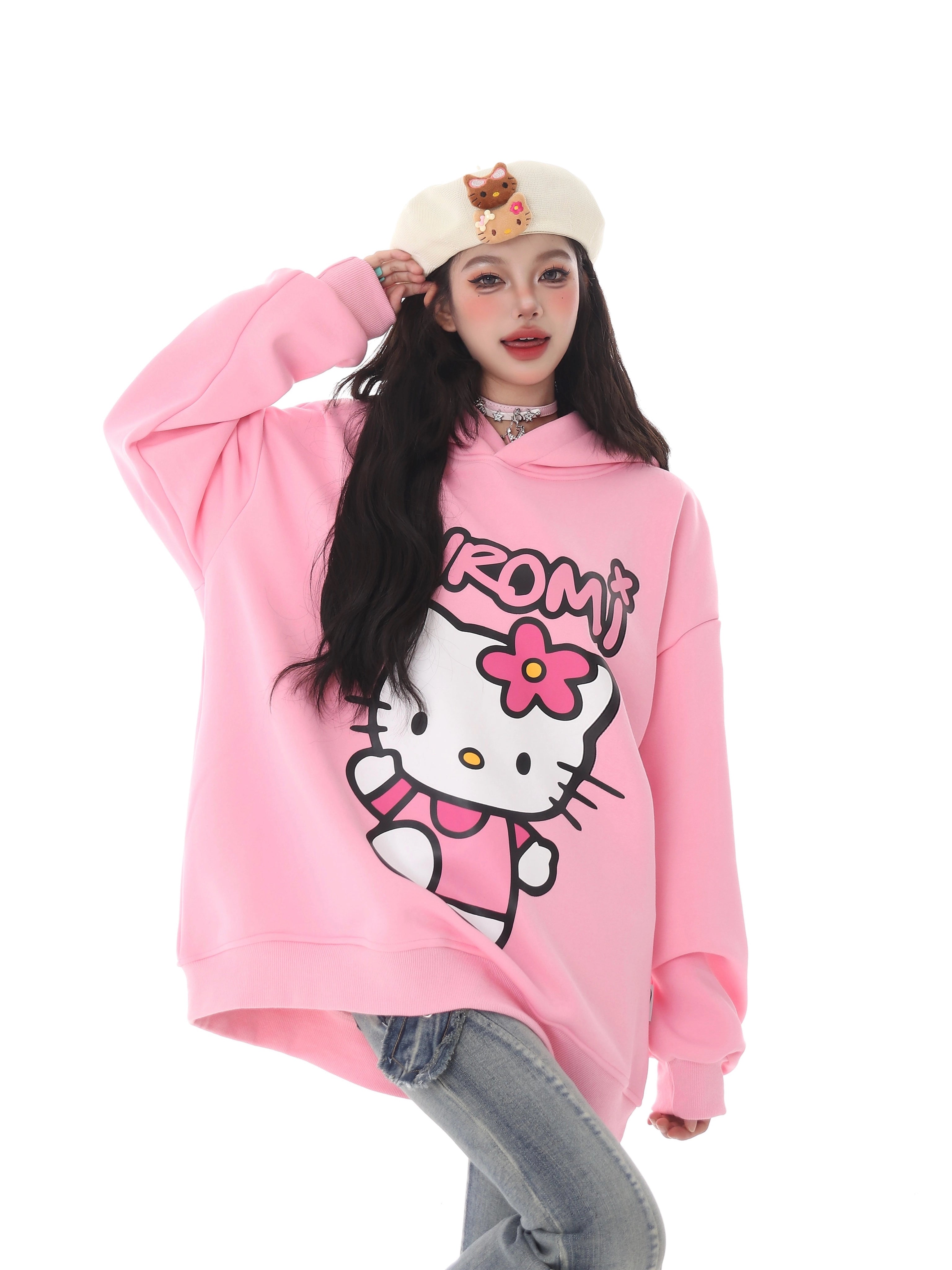 Embracing kawaii fashion, they wear a pink Seakoff Kawaii Hello Kitty Oversized Hoodie paired with blue jeans and a white beret sporting a small toy bear. Posing stylishly against a plain white background, it&