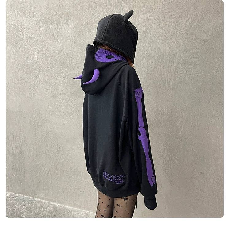 A person in a Seakoff Dark Skull Demon Hoodie, sporting horn-like details and purple designs, paired with star-patterned sheer tights, stands against a plain textured wall, capturing anime-inspired style while facing away from the camera.