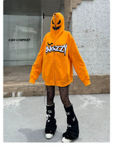 Wearing the Seakoff Halloween Pumpkin Hoodie—an oversized orange zip-up sweatshirt—they pair it with black star-patterned tights and leg warmers, standing by a gray building displaying "Can Company.