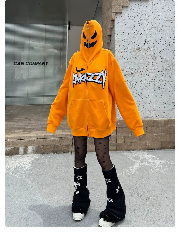 Wearing the Seakoff Halloween Pumpkin Hoodie—an oversized orange zip-up sweatshirt—they pair it with black star-patterned tights and leg warmers, standing by a gray building displaying "Can Company.