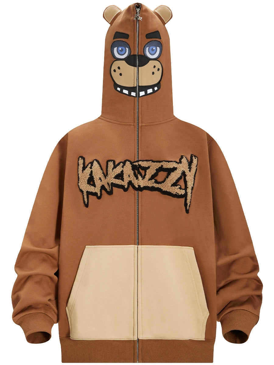 The Seakoff Freddy-Inspired Hoodie is a 400GSM oversized brown hoodie with a zip-up hood creating a bear face, featuring blue eyes and a smiling mouth. It includes beige pockets and stylized Five Nights at Freddy&