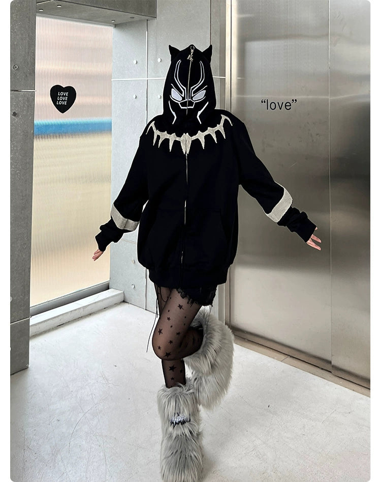 Indoors, someone models an oversized 400GSM Black Panther-inspired hoodie with ear design by Seakoff, paired with star-patterned tights and fuzzy boots. Heart-shaped "love" decor on the wall captures streetwear fans&