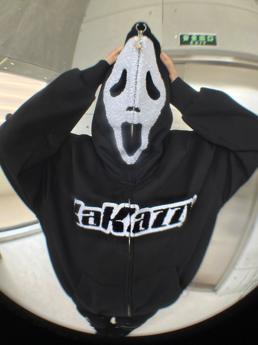 A person wears a Seakoff Scream-Inspired Hoodie, an oversized black 400GSM zip-up streetwear sweatshirt, and a Ghostface full-face mask. They grasp the mask&
